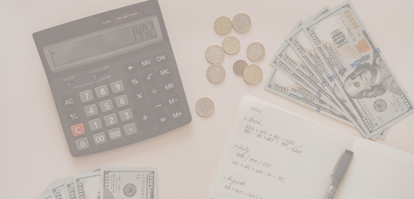 A calculator, money, notepad, and pen laid out to make a budget
